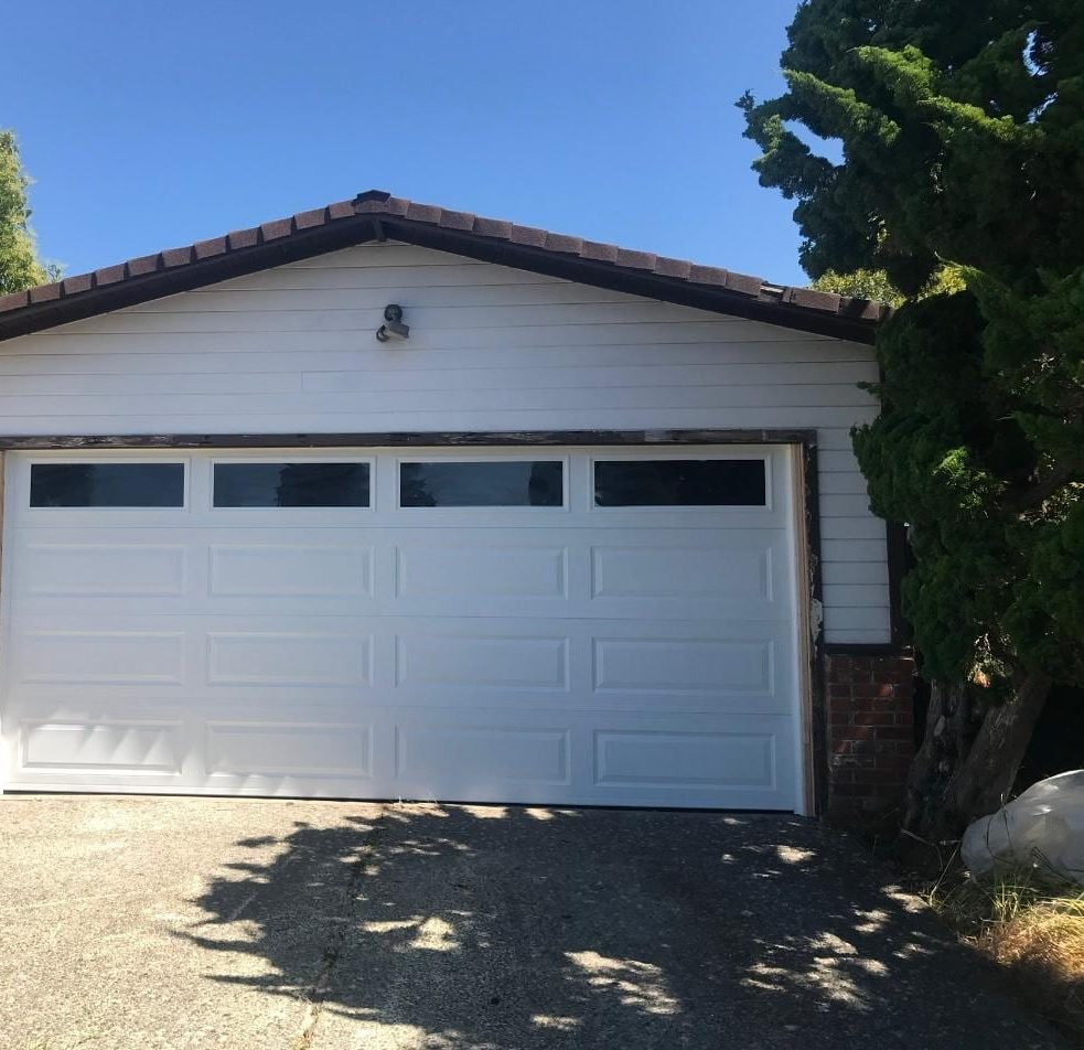 White steel garage door with a row of windows on a one-storey house with a tile roof