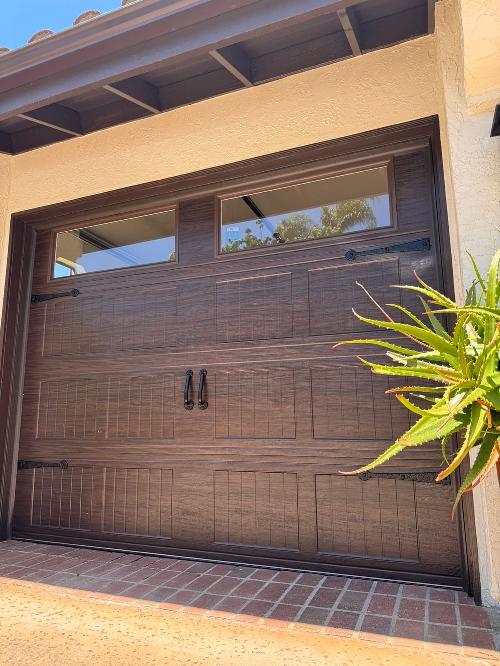 Dark carriage-style wood garage door with a glass top row