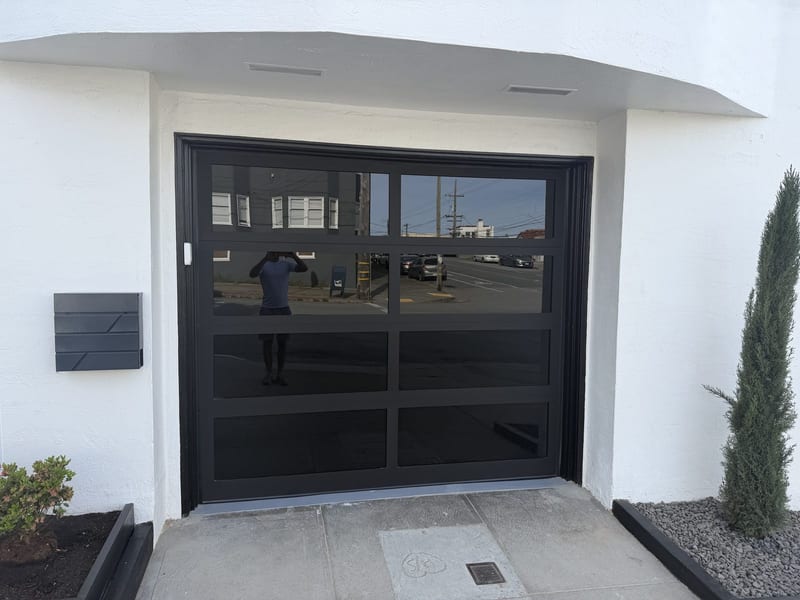 Black full-view glass garage door we installed on a white stucco garage